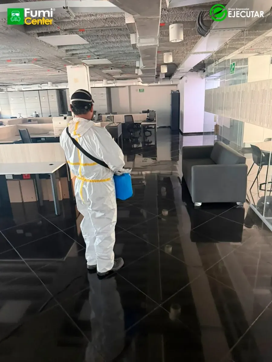 Técnico de FumiCenter con traje de protección aplicando en oficinas y áreas técnicas de la DIAN en Santa Marta