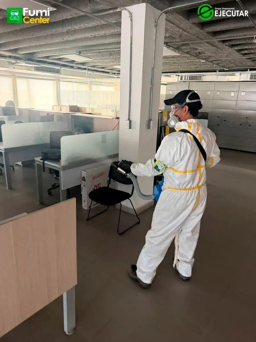 Técnico de FumiCenter con traje de protección aplicando en oficinas y áreas técnicas de la DIAN en Santa Marta