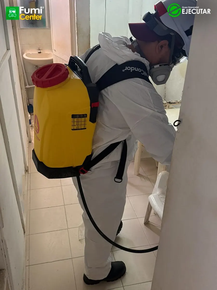 Técnico de FumiCenter con traje de protección y pulverizador aplicando en instalaciones del INPEC