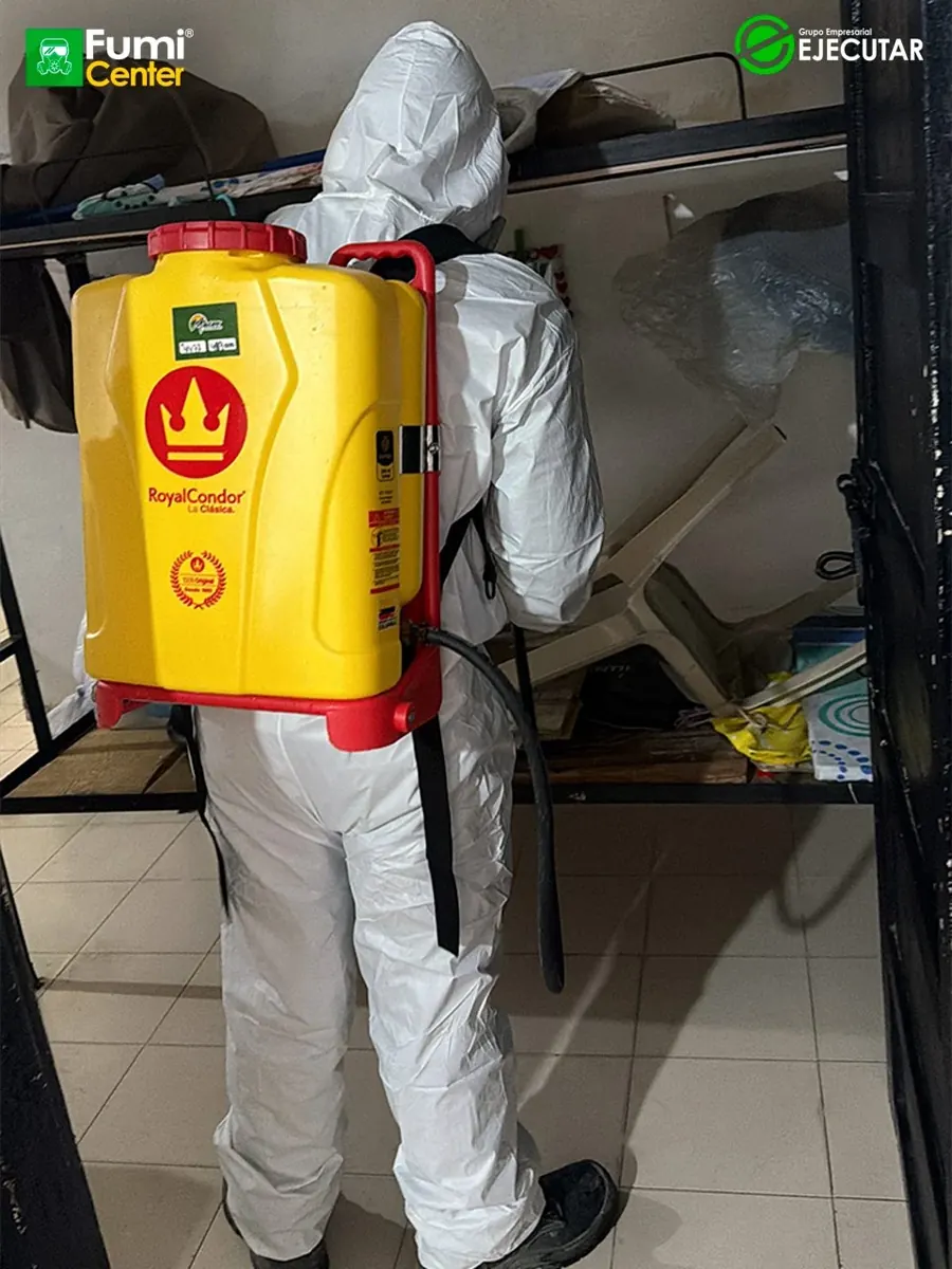 Técnico de FumiCenter con traje de protección y pulverizador aplicando en instalaciones del INPEC